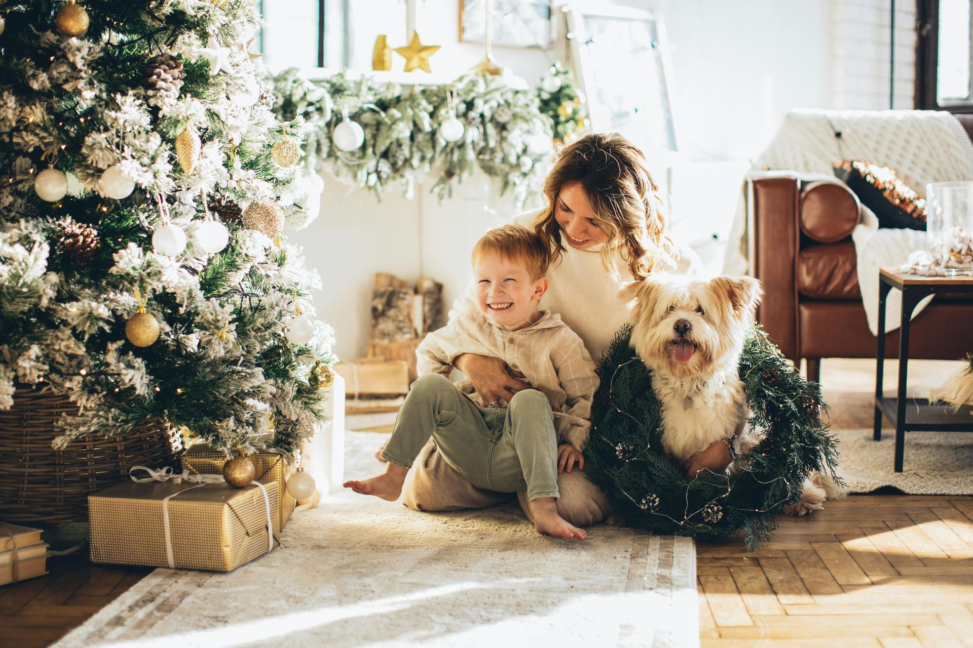 Mother, child, and dog enjoying Christmas morning by the decorated tree at home.