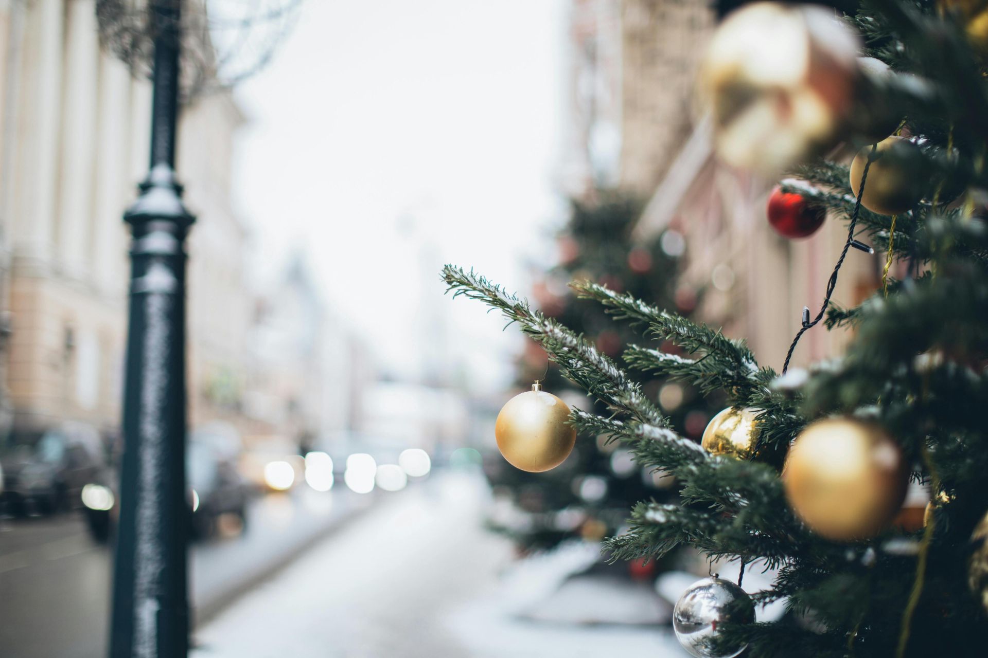 Festive Christmas decorations with hanging baubles on a snowy street, captured in soft focus.