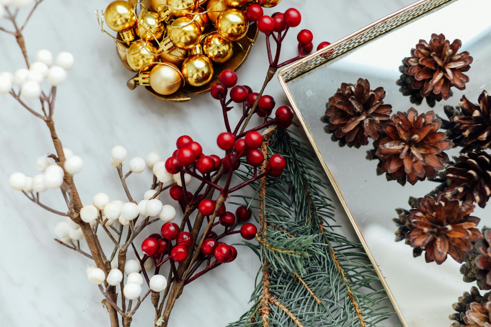 A stylish flat lay featuring holiday decorations with pinecones, berries, and ornaments.